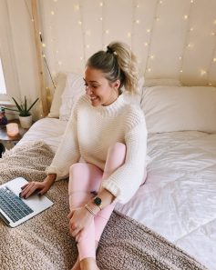 Image of Tatum in an influencer post sitting on bed looking at laptop