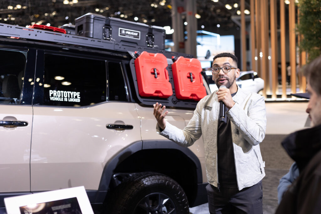 male automotive product specialist in front of vehicle with microphone